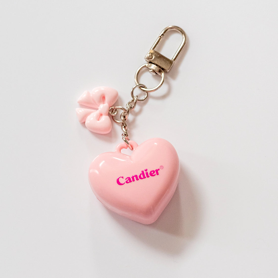 Pink heart-shaped keychain with floral charm on a light gray background