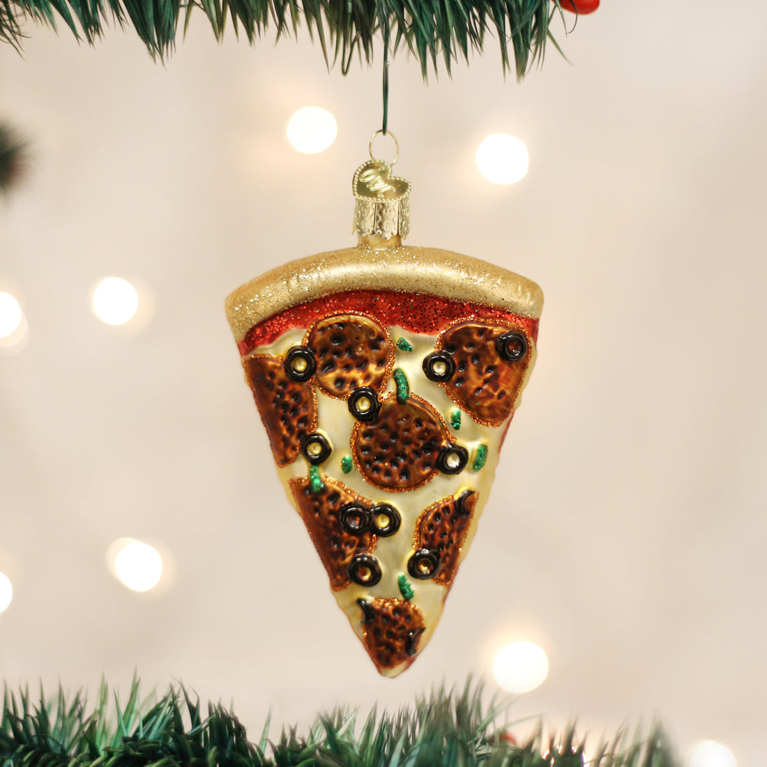 Pizza slice ornament hanging on a Christmas tree with lights in the background