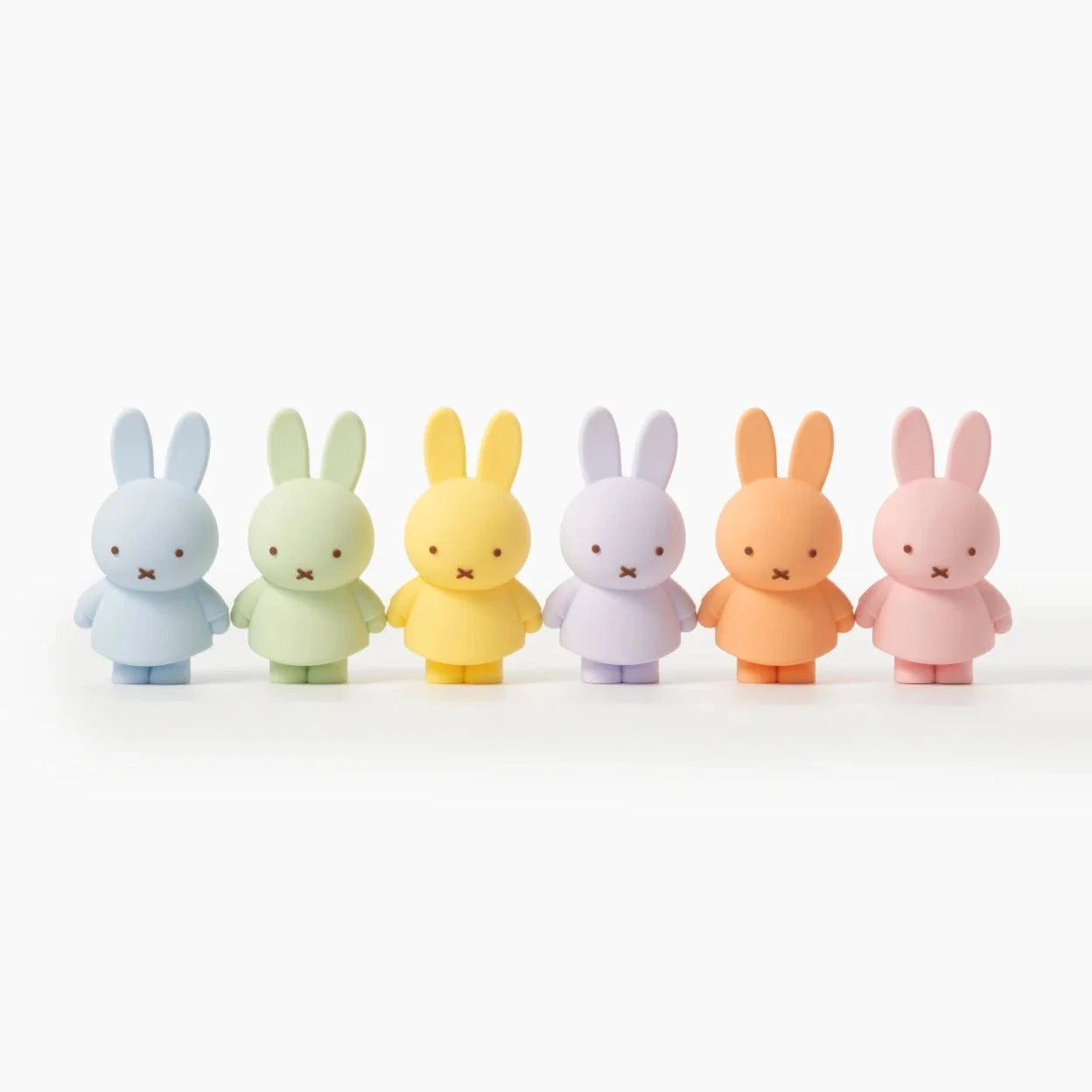 Five colorful bunny figurines in a row on a white background