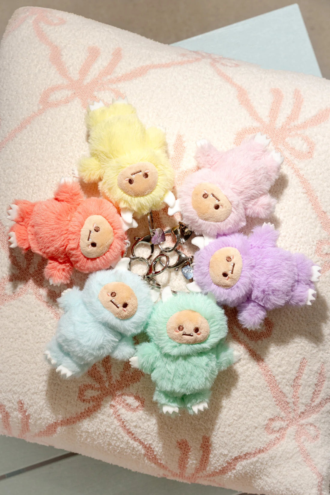 Set of colorful plush yeti keychains on a textured surface