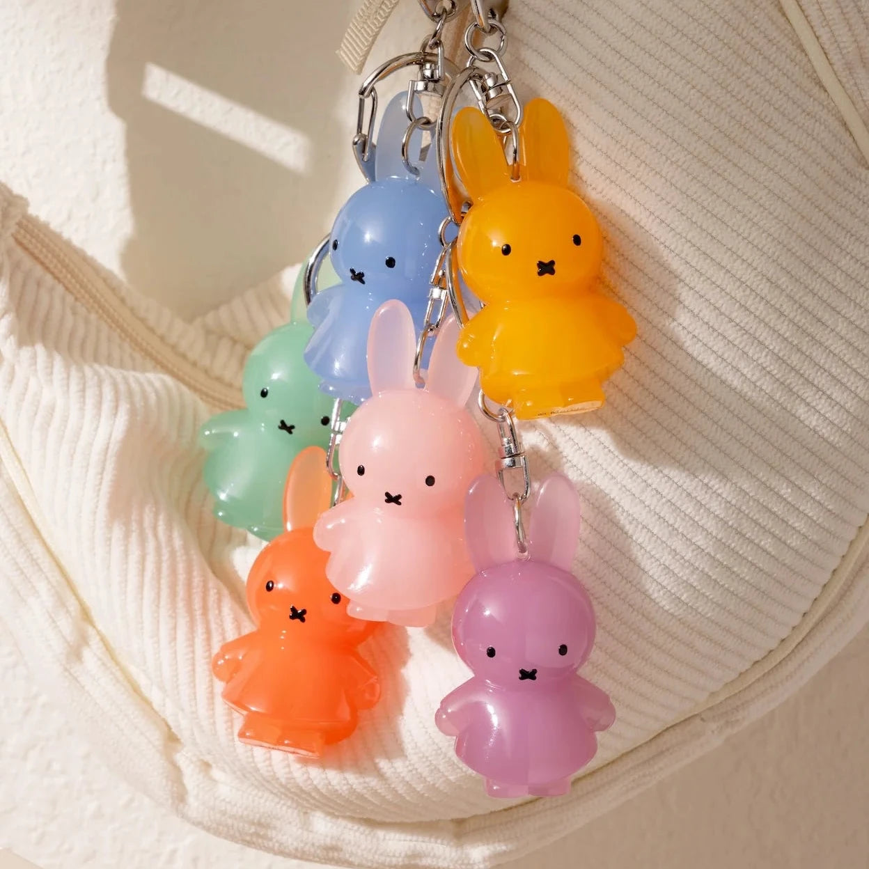 Colorful bunny-shaped keychain hanging on a textured beige surface