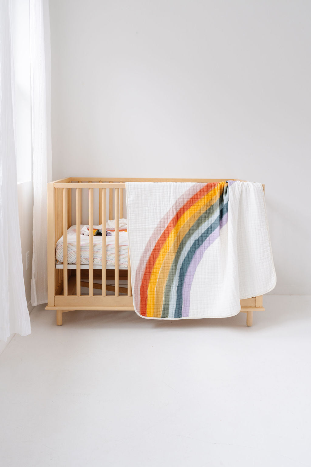 Nursery with a wooden crib and rainbow-patterned blanket