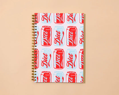 Notebook with Diet Coke can pattern on a beige background