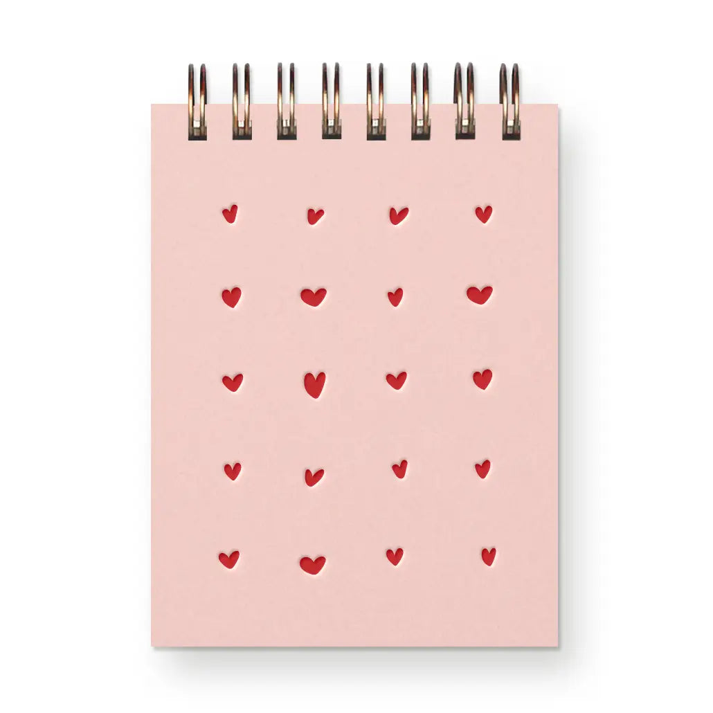 Pink notebook with red heart patterns on a white background