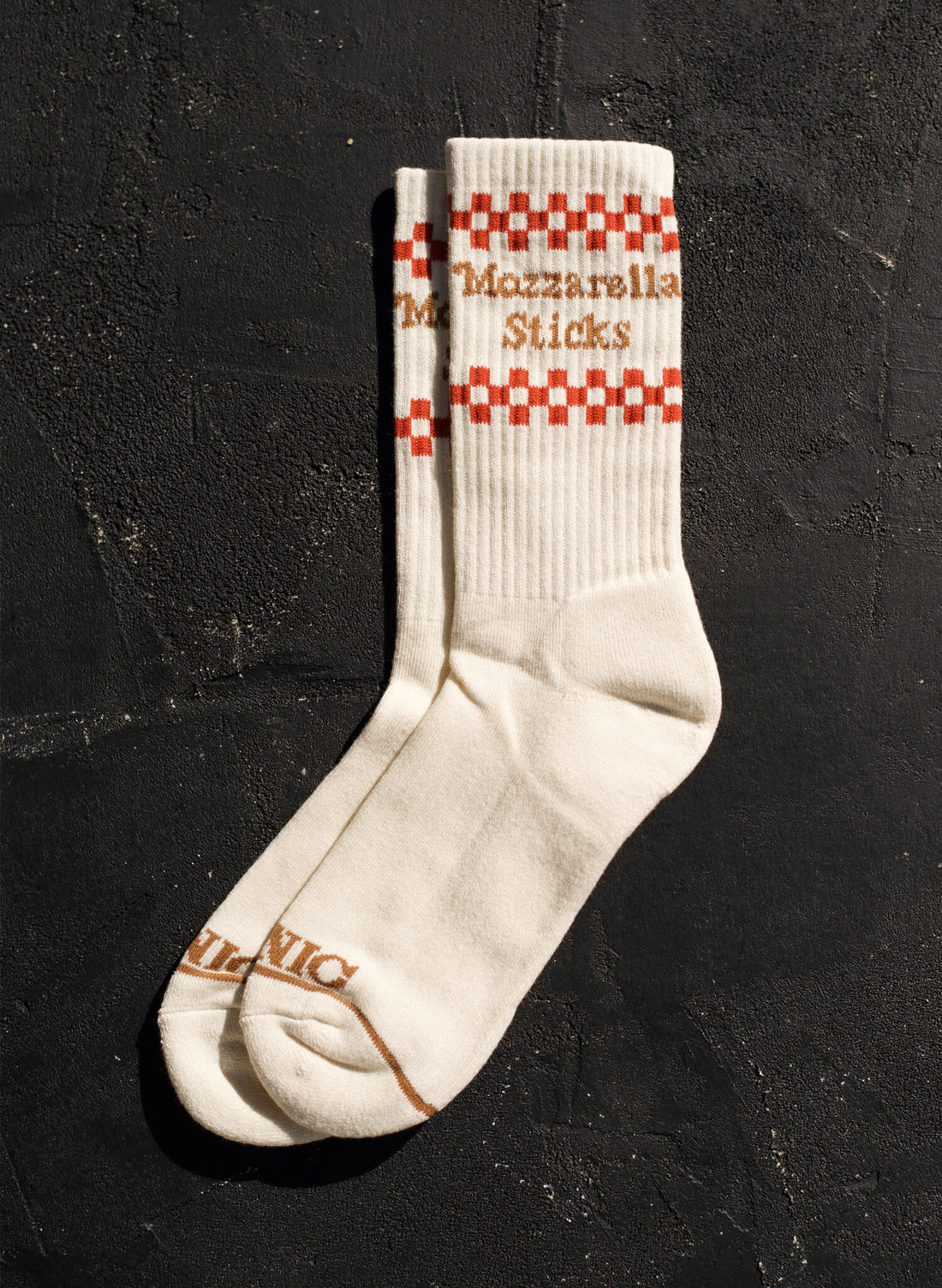 White socks with red and brown checkered pattern and text on a dark background