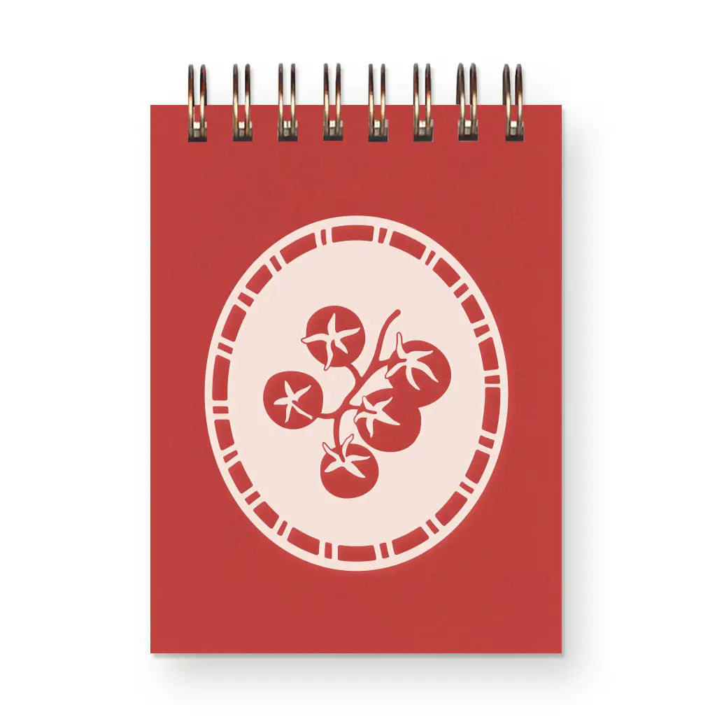 Red notebook with a white tomato design on a white background